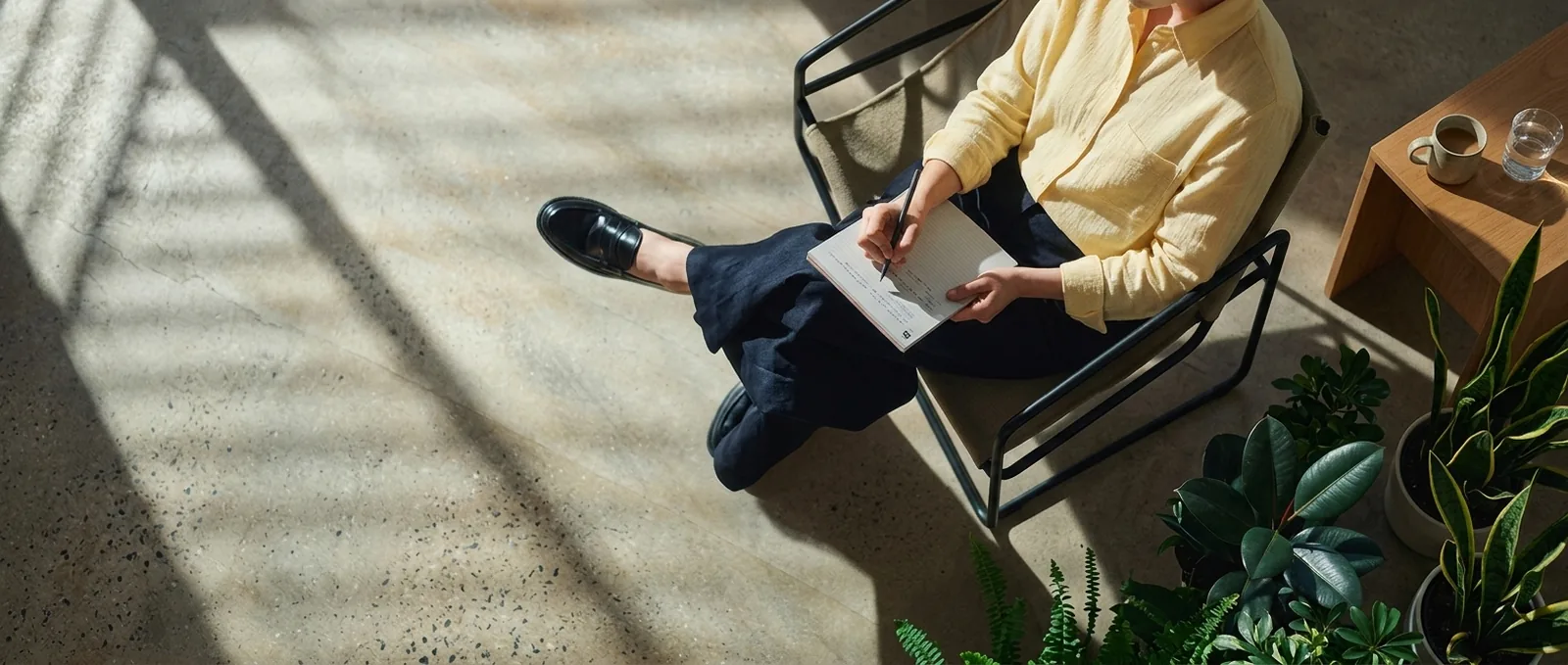 A therapist sitting in a sunlit room, writing in a notebook